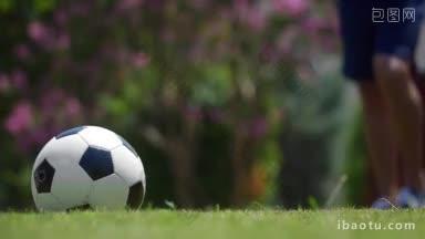慢动作特写镜头，一个人跑和踢足球躺在绿色的草地上，只有脚可以看到